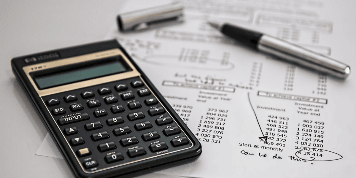Calculator and Financial Documents with Handwritten Notes and a Silver Pen Nearby.